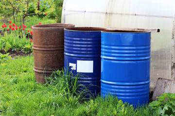 Three metal water barrels in the garden