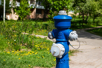A bright blue fire hydrant is prominently sitting beside the road