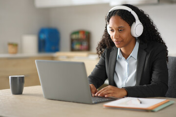 Black executive tele working in the kitchen at home