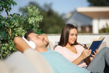 Couple enjoying of different hobbies sitting in a terrace