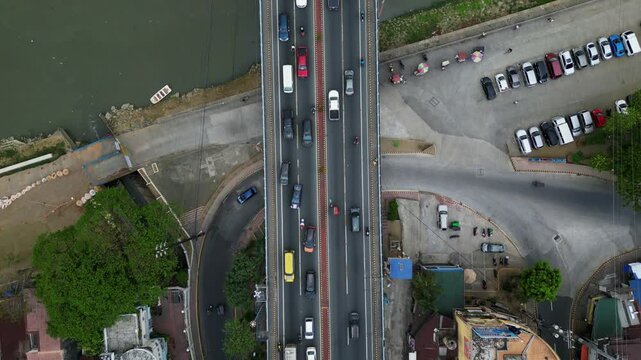 Flyover shot of a busy city bridge and interchange crossing Marikina River, NCR, Philippines - aerial top-down