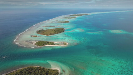 Stunning aerial perspective of tropical islands string forming an atoll and ocean bay strait...