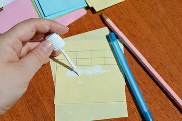 Hand applying correction fluid to paper table on sticky note. Office supplies, error correction,...