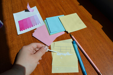 Hand applying correction fluid to paper table on sticky note. Office supplies, error correction,...
