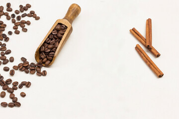 Grains of coffee in wooden scoop and on table.