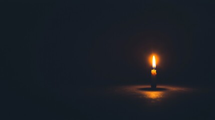 Fototapeta premium A single candle illuminates a dark room.