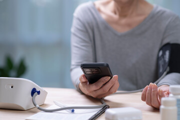 Senior Asian Woman taking blood pressure test on phone.