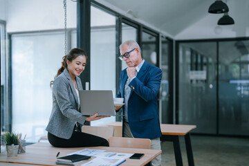 Businesswoman presenting a laptop to businessman enjoying coffee in a modern office, collaborating on strategies for a new project while discussing innovative ideas
