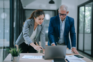 Business people working together analyzing financial charts and graphs using laptop computer and discussing new marketing strategy in modern office