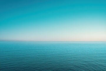Obraz premium Expansive view of a tranquil ocean meeting a clear, vibrant sky. A flat horizon separates the deep blue water from the pale, soft blue of the sky, creating a sense of vastness and calmness