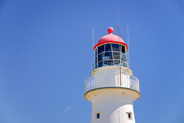 lighthouse against blue sky, daylight view, close closeup light, maritime hazard warning beacon