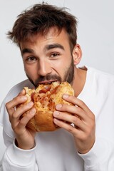 A man is eating a sandwich. The sandwich is half eaten. The man is smiling. Scene is happy and relaxed