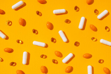 Different capsules vitamins, natural supplements, nutraceuticals on yellow background top view. Tablets, pills close up. Medical pharmaceutical background. Solar lighting