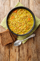 Lentil soup with coconut milk, carrots, onions, turmeric, lemon and ginger close-up in a plate on the table. Vertical top view from above