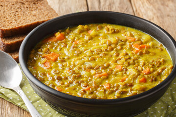 Vegan detox lentil soup with coconut milk, carrot, onion, turmeric, lemon and ginger close-up in a plate on the table. Horizontal