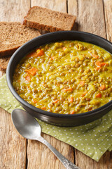 Lentil soup with coconut milk, carrots, onions, turmeric, lemon and ginger close-up in a plate on the table. Vertical