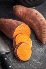 Raw sweet potatoes on kitchen table.