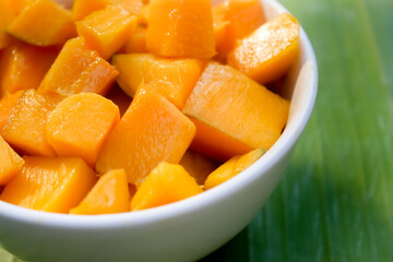 close up of a bowl of cut mangoes on a banana leaf background.tropical fruit.