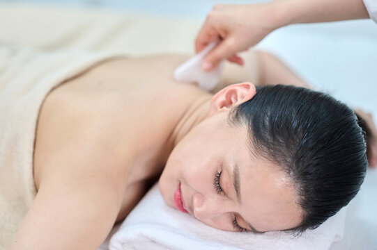 Female Gua Sha Back and Shoulder Massage Therapy with Oil at Spa