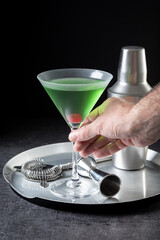 Hand catching a Japanese slipper cocktail on black background