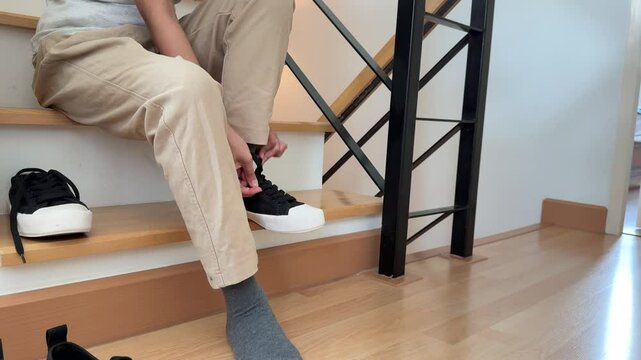 The Southeast Asian teenage girl is wearing socks and shoes on the stairs at home.