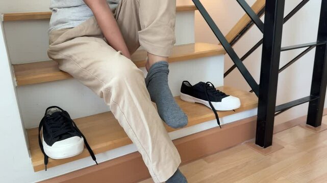 The Southeast Asian teenage girl is wearing socks and shoes on the stairs at home.