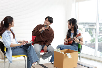Happy young Asian band enjoy singing and playing music together for donations. Three cheerful teenagers singing, playing keyboard and ukulele for charitable donation. People with music instrument.