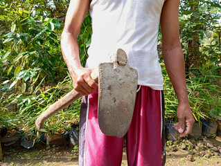 a man in white holding a hoe