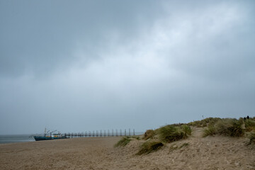 Eierland, De Cocksdorp, Texel, The Netherlands, Oktober 28th, 2024, A serene beach landscape featuring a moody sky, soft dunes, and a distant pier subtly appearing on the horizon