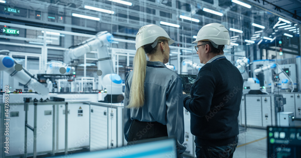 Poster Young Engineer and Technician Having a Conversation and Using a Laptop Computer. Industrial Specialists Monitoring, Analyzing Conditions at a Modern Electronics Factory with Automated Assembly Line