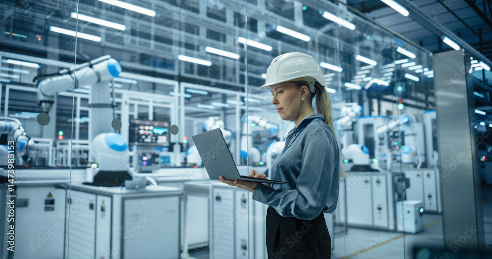 Aufkleber caucasian female engineer in a hard hat using a laptop computer to monitor robotic arms in an advanc