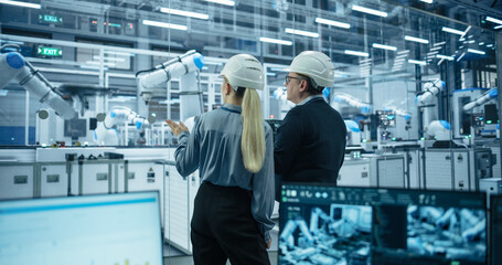 Female and Male Industrial Engineers Monitoring and Analyzing Conditions at a Modern Tech...
