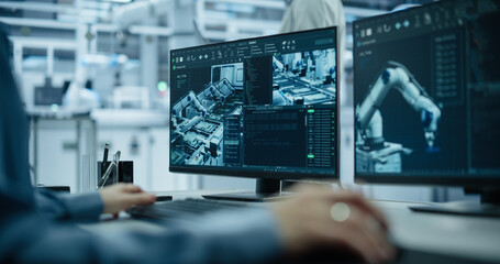 Portrait of a South Asian Engineer in a Hard Hat Working in an Industrial Facility. Indian Industrial Manager Using Laptop Computer to Monitor Robotic Arms in a Futuristic Electronics Factory