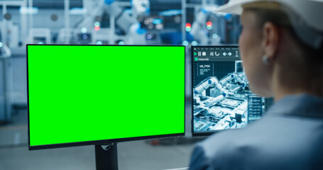 Female Industrial Specialist Working on a Desktop Computer with Green Screen Mock Up Display....