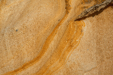 Natural texture background of sandstone rocks with lines, curves, prints in the As Amoeiras and Formosa beach cliffs in Santa Cruz, Portugal.
