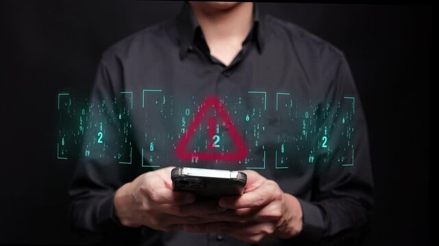 A person in a black shirt is typing on a mobile phone with a futuristic screen displaying a red exclamation symbol, indicating a cyber threat or hacking attempt.