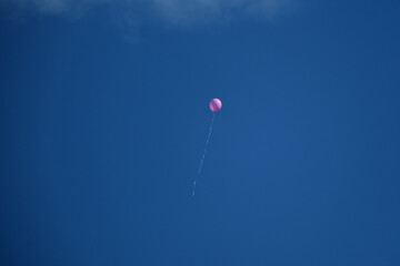 Pink balloon flying in the blue sky with white clouds on a sunny day