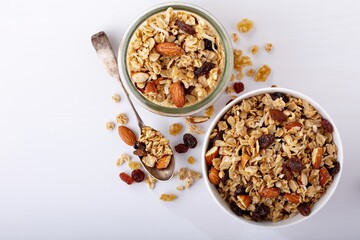 Homemade granola with coconut, raisins and almonds for breakfast in a jar and a bowl with milk overhead