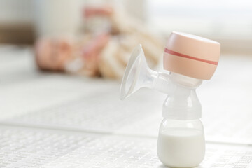 Electric breast pump with baby in background. Baby care concept.