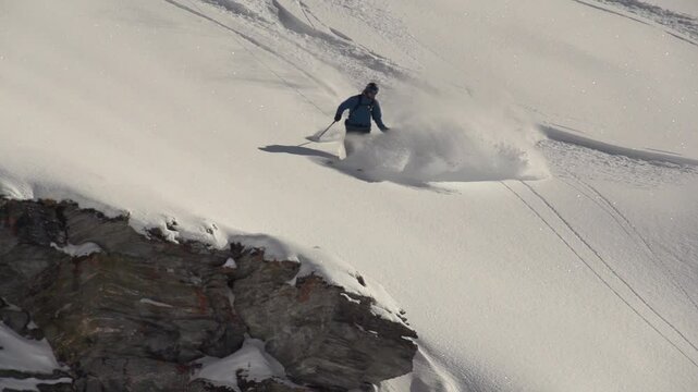 Saut de barre rocheuse dans poudreuse en ski