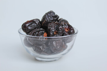Ajwa dates or ajwa khajur, in transparent bowl, isolated on white background