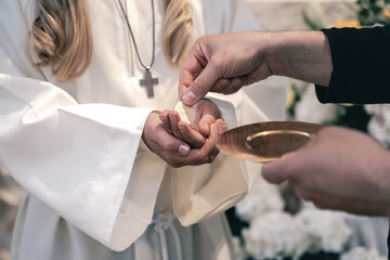 A priest offers the Holy Communion host to a young girl during a solemn church service ceremony