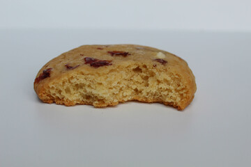 A bitten white choco soft cookie with almond and berry cuts, isolated on white background