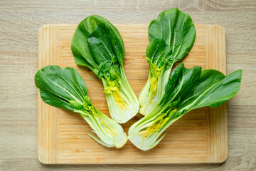 Cut green pak choi cabbage leaves on wooden board. Fresh chinese cabbage pak choi on wooden board. top view.