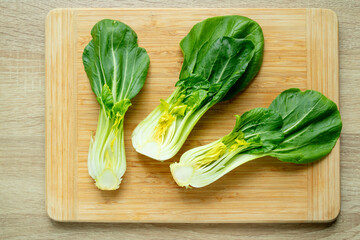 Cut green pak choi cabbage leaves on wooden board. Fresh chinese cabbage pak choi on wooden board. top view.