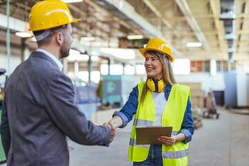 Construction Managers Handshaking in Industrial Warehouse with Yellow Safety Helmets