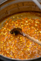 Cooking a savory stew with diced vegetables simmering in a large pot on the stove during a warm afternoon
