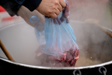 Cooking meat in a steaming pot during a cultural festival in a vibrant outdoor market setting