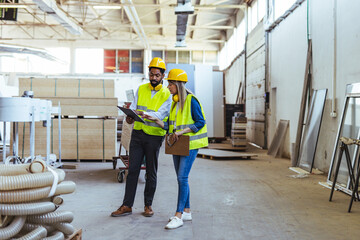 Two Engineers Discussing Work in a Spacious Industrial Warehouse
