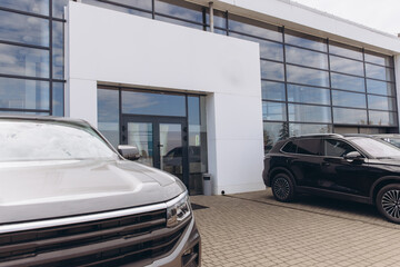 Cars parked in front of modern car dealership showroom building
